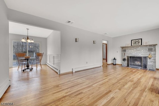 living room with light wood-style floors, a fireplace with flush hearth, and a baseboard heating unit