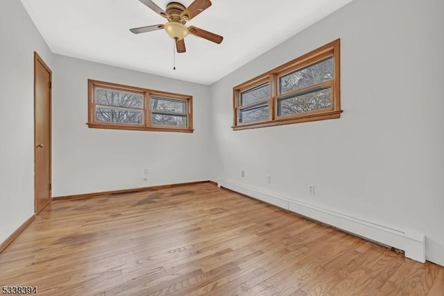 spare room with light wood-style floors, baseboard heating, baseboards, and a ceiling fan