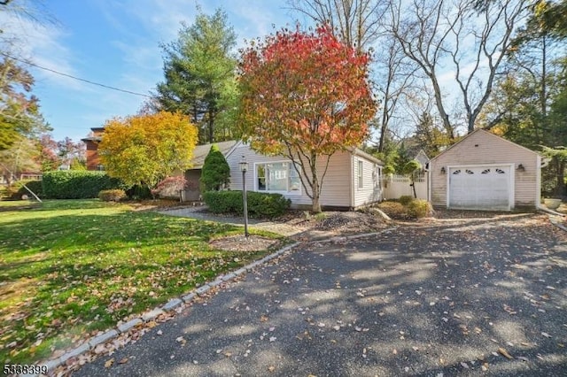 view of front of house with driveway, a front lawn, an outdoor structure, and a detached garage