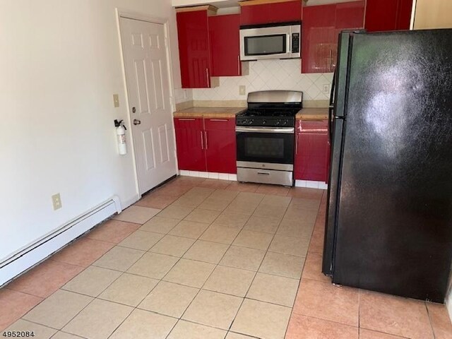 kitchen with light tile patterned floors, red cabinetry, appliances with stainless steel finishes, and a baseboard radiator