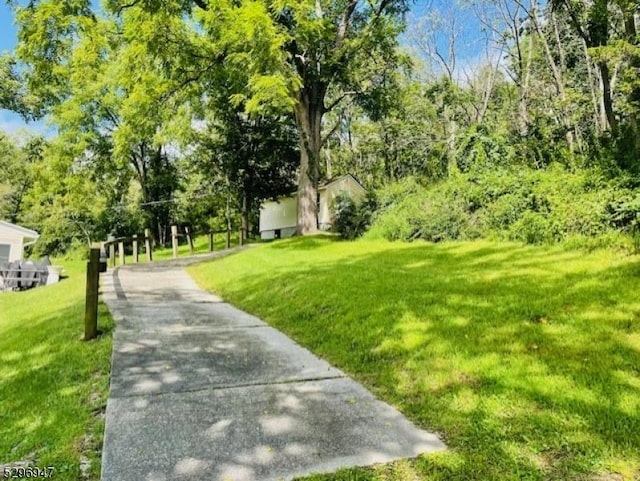 view of property's community featuring a lawn and concrete driveway
