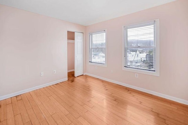 unfurnished bedroom featuring a closet, light wood-style flooring, and baseboards