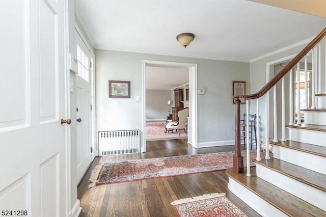 foyer entrance featuring ornamental molding, radiator, dark wood-style flooring, and stairs