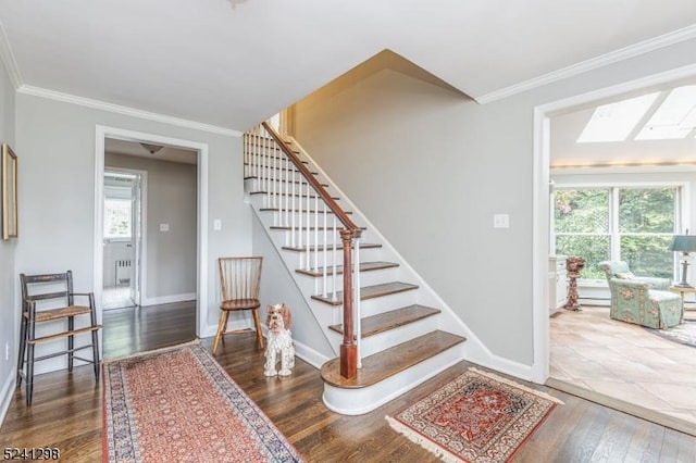 staircase featuring a skylight, plenty of natural light, crown molding, and wood finished floors