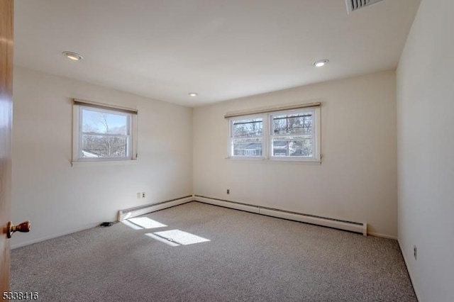 carpeted empty room featuring plenty of natural light and a baseboard heating unit