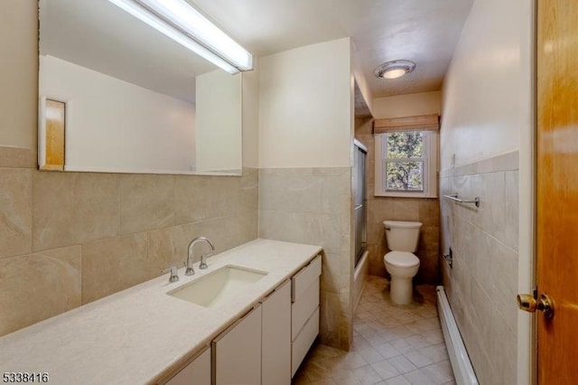 full bathroom featuring toilet, shower / bath combination with glass door, tile walls, baseboard heating, and vanity