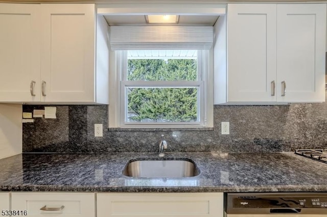 kitchen with dishwasher, white cabinetry, sink, and dark stone countertops