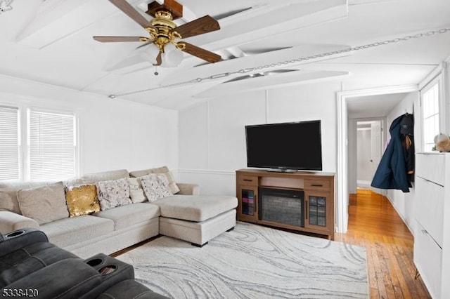 living room featuring ceiling fan, beamed ceiling, and light hardwood / wood-style floors