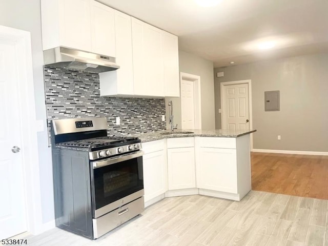 kitchen with sink, stainless steel gas range oven, tasteful backsplash, light stone countertops, and white cabinets