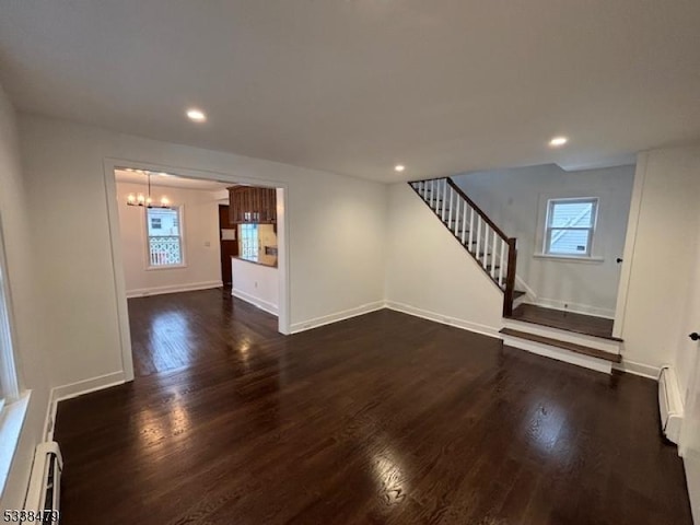 unfurnished living room with a baseboard heating unit, dark hardwood / wood-style floors, and a notable chandelier