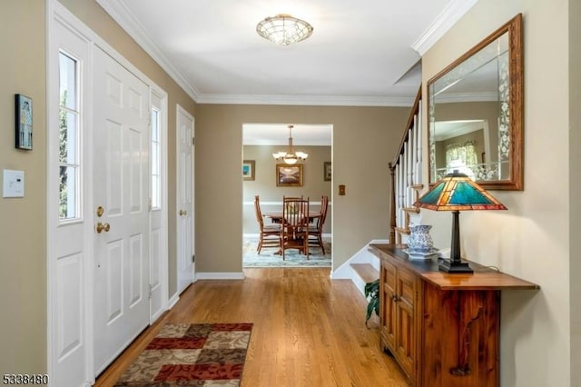 entrance foyer with a healthy amount of sunlight, light wood finished floors, stairway, and ornamental molding