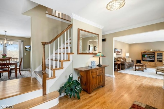 stairs featuring baseboards, crown molding, a chandelier, and wood finished floors