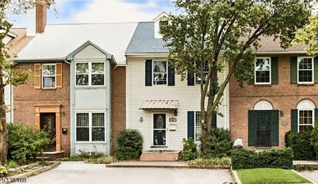 townhome / multi-family property with brick siding and a chimney