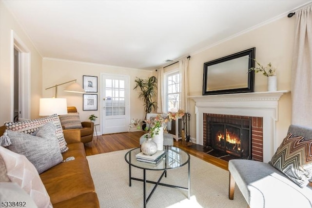 living room with hardwood / wood-style flooring, crown molding, and a brick fireplace