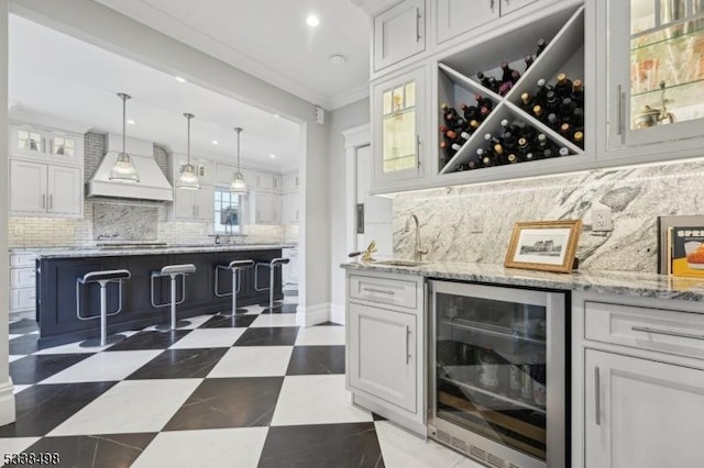 bar featuring custom range hood, white cabinets, decorative light fixtures, crown molding, and wine cooler