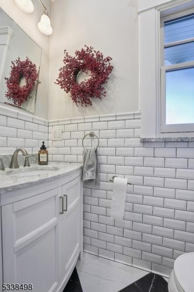 bathroom with tile walls, vanity, and toilet