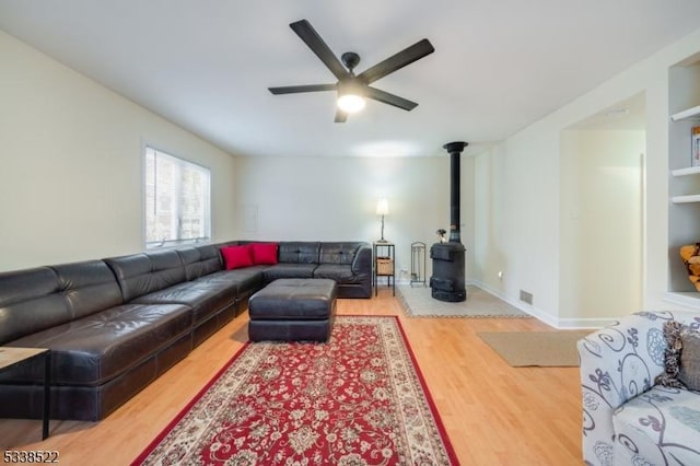 living room featuring a wood stove, hardwood / wood-style floors, and ceiling fan