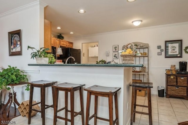 kitchen featuring light tile patterned floors, dark countertops, freestanding refrigerator, a peninsula, and crown molding