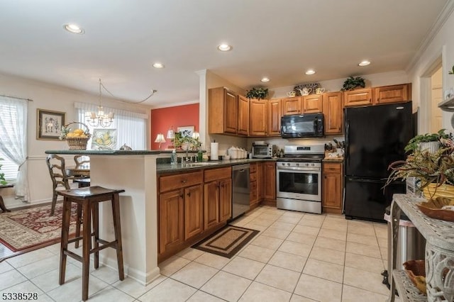 kitchen featuring black appliances, brown cabinetry, a peninsula, and decorative light fixtures