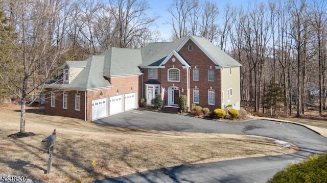 view of front of house with driveway, an attached garage, and brick siding