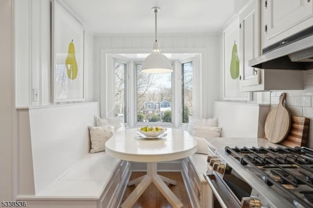 kitchen featuring pendant lighting, white cabinetry, tasteful backsplash, stainless steel gas range oven, and breakfast area