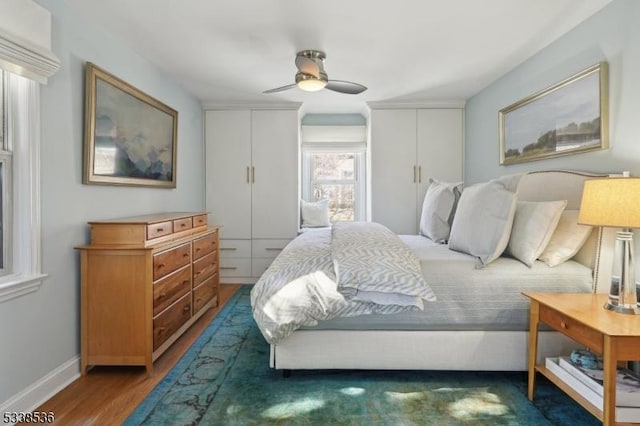 bedroom featuring multiple closets, ceiling fan, and dark hardwood / wood-style floors