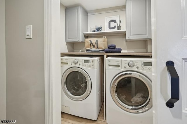 laundry area with cabinets and washing machine and clothes dryer