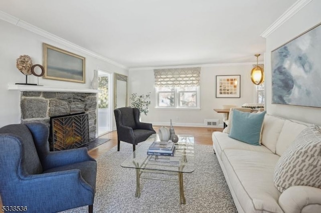 living room featuring ornamental molding, a stone fireplace, and wood-type flooring