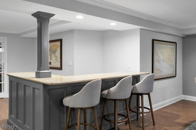 bar featuring gray cabinets, crown molding, dark hardwood / wood-style flooring, and ornate columns