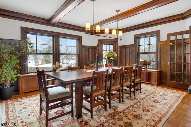 dining area with radiator, a healthy amount of sunlight, a wainscoted wall, and beamed ceiling