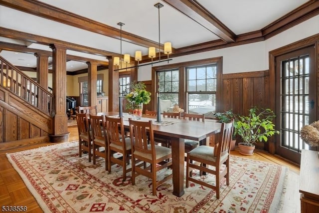 dining room with decorative columns, wainscoting, stairway, ornamental molding, and beam ceiling