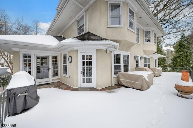 snow covered property with stucco siding