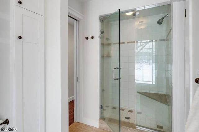 full bath featuring a shower stall and baseboards