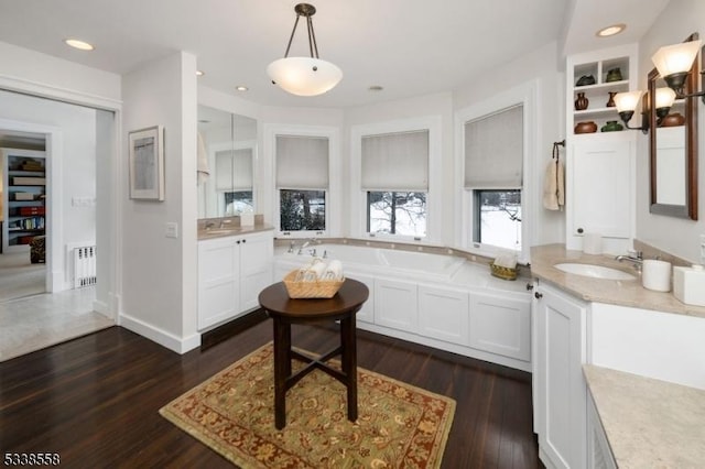 kitchen with radiator heating unit, dark wood-style flooring, hanging light fixtures, white cabinetry, and a sink