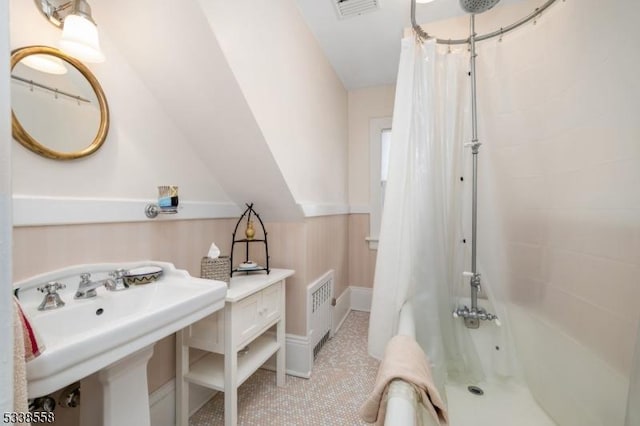 bathroom featuring lofted ceiling, shower / tub combo, a sink, and visible vents