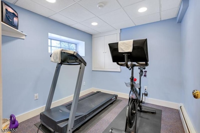 exercise room featuring a paneled ceiling, a baseboard radiator, baseboards, and recessed lighting