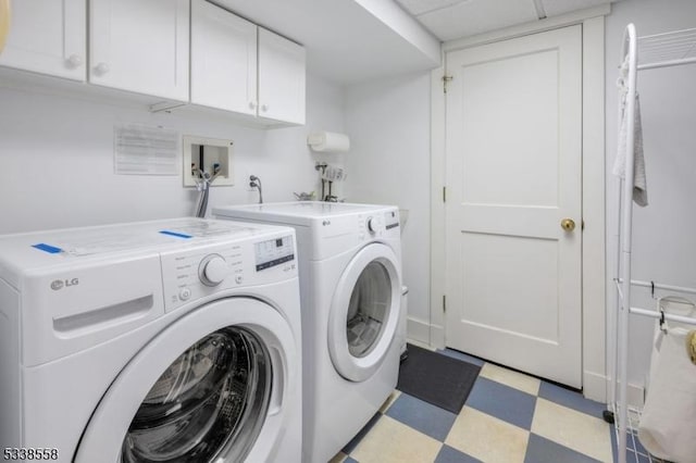 washroom with washer and dryer, cabinet space, and light floors