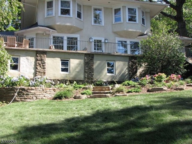 rear view of property featuring a lawn and stucco siding