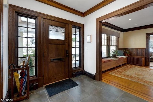 foyer featuring a wainscoted wall, ornamental molding, and radiator heating unit