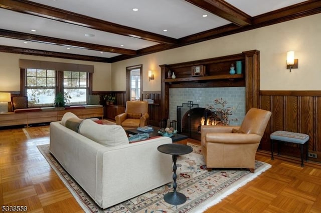 living area featuring wainscoting, beamed ceiling, wooden walls, and a tiled fireplace