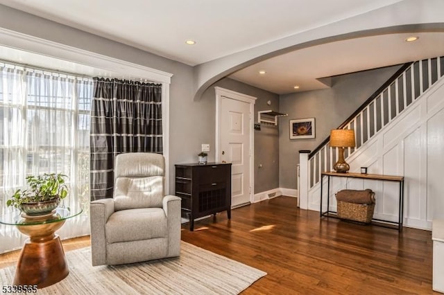 living area featuring stairs, arched walkways, wood finished floors, and recessed lighting