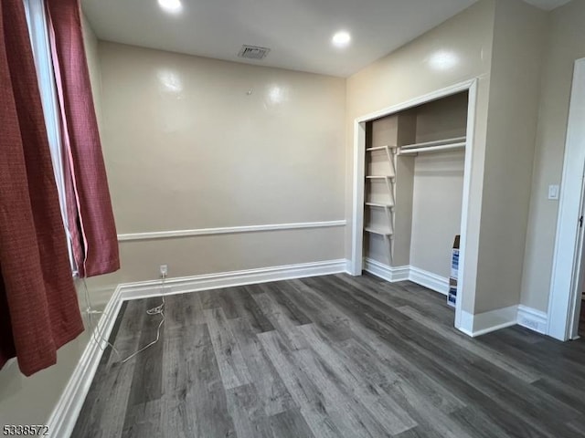 unfurnished bedroom featuring dark hardwood / wood-style flooring and a closet