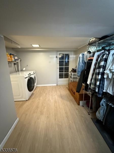 laundry room featuring washer and dryer, laundry area, wood finished floors, and baseboards