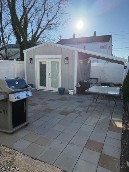 back of property with a patio area, french doors, an outbuilding, and fence