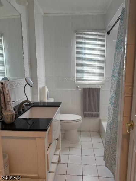 full bathroom with tile patterned flooring, vanity, tile walls, and crown molding