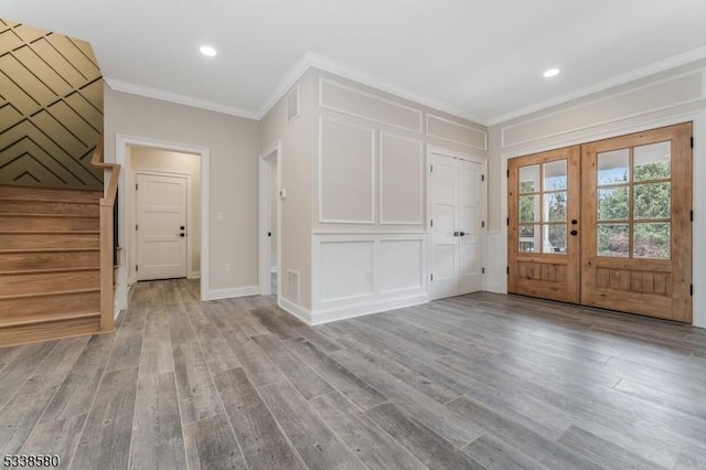 entrance foyer featuring light wood-style flooring, stairs, crown molding, french doors, and a decorative wall