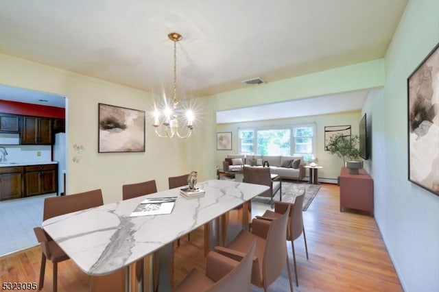 dining area featuring an inviting chandelier, sink, and light hardwood / wood-style floors