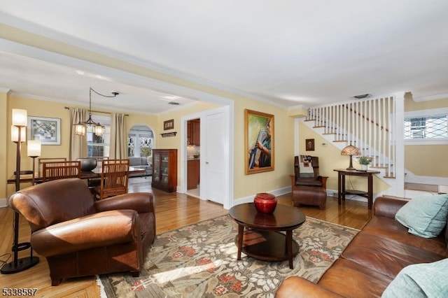 living area with stairs, ornamental molding, baseboards, and wood finished floors