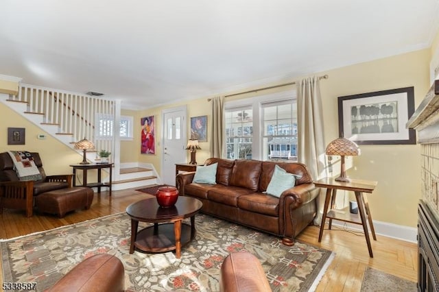 living room with a fireplace with flush hearth, stairway, baseboards, and wood finished floors