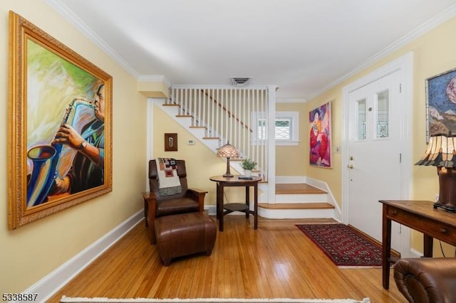 entrance foyer with ornamental molding, stairway, baseboards, and wood finished floors